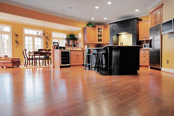 Open floor plan interior with polished hardwood floors showcases an impressive reclaimed wood kitchen island, black dining table set and sliding doors to fenced backyard. Northwest, USA