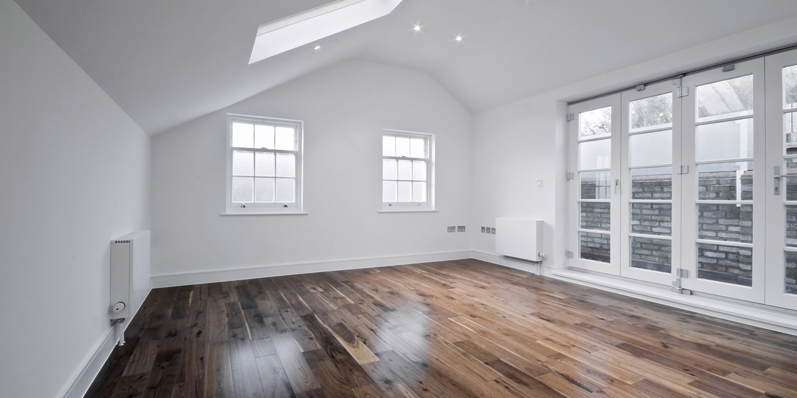 empty unfurnished loft room with roof window and solid wood floor